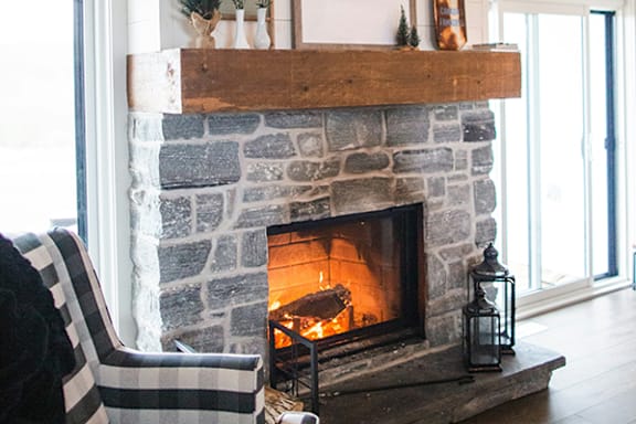 a stone fireplace with a wooden mantel and a roaring fire