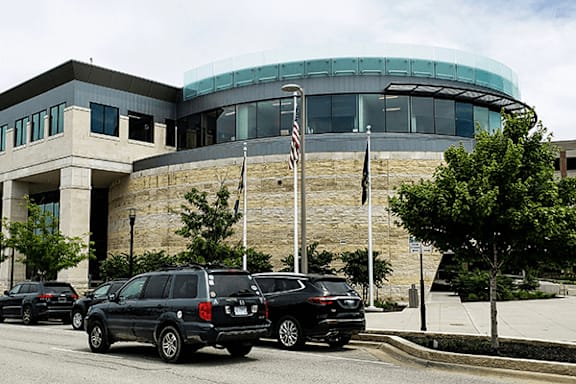 A black SUV is parked in front of a building with a flag on a pole.
