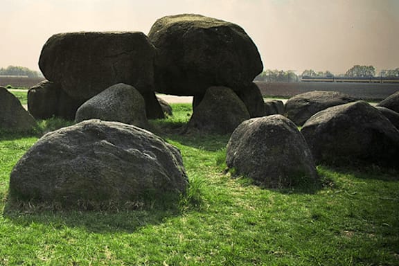 A group of large rocks are in a grassy field.