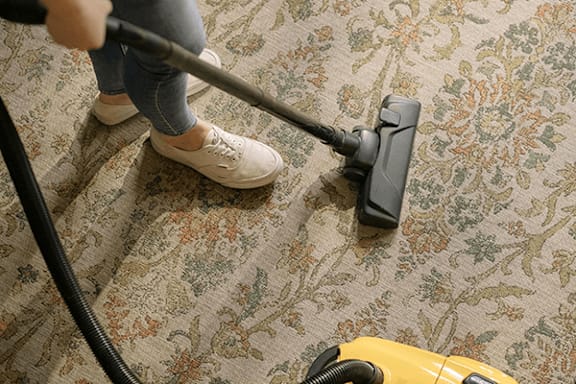 A person vacuuming a floral carpet.