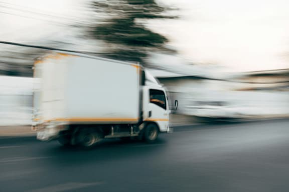 A white truck is in motion on a road.
