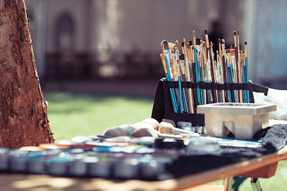 A table with a variety of colorful sticks and a container of something white is set up outside.