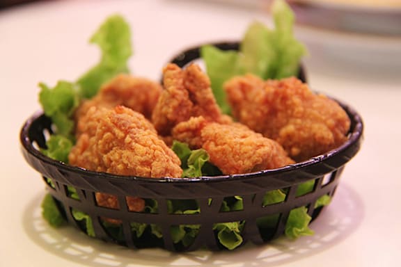 Fried chicken in a black basket on a white plate.