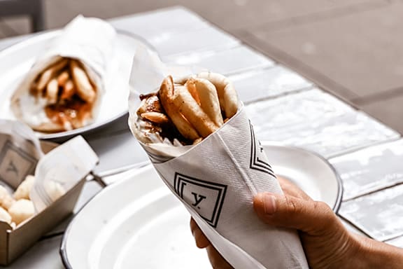 a hand holding a bag fries on a table