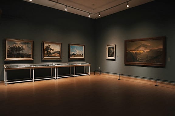 A room with a long table and paintings on the wall.