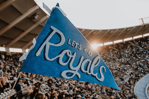 A blue flag with the words "Let's Royals" written on it is being held up in a stadium.