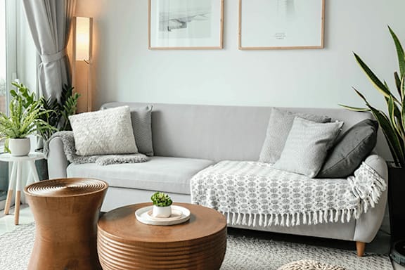 A grey couch with a white throw blanket on it.