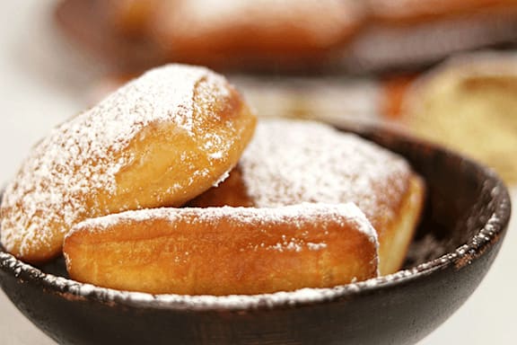 A bowl of sugared doughnuts with a blurred background.