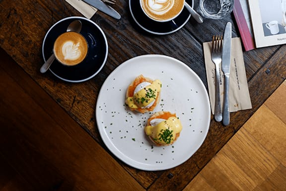 A white plate with two deviled eggs on top of a wooden table.