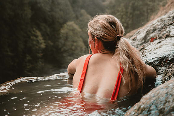 A woman in a red bikini is sitting in a body of water.