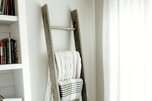A chair with a blanket draped over it is leaning against a wall.