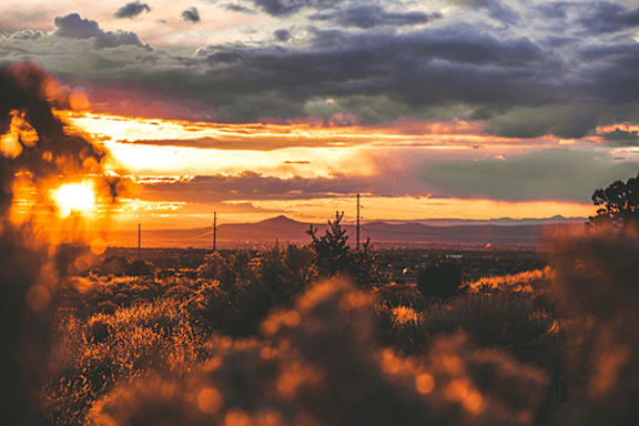 A sunset over a field with a mountain in the distance.