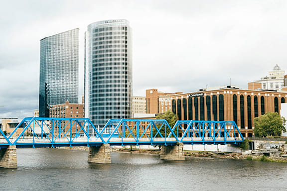 A blue bridge crosses a body of water with buildings in the background.