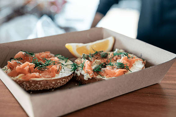 Two bagels with salmon and dill in a box.