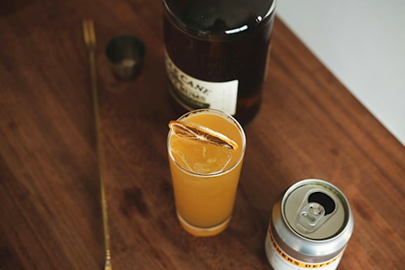 A can of beer is next to a glass of beer on a wooden table.