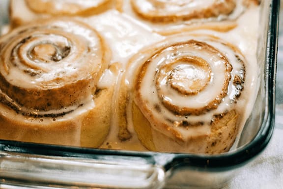 A glass baking dish containing cinnamon rolls with a creamy white icing.