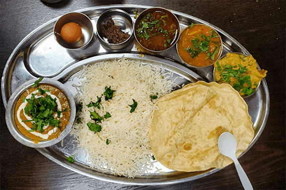 A silver tray with rice, curry, and flatbread.
