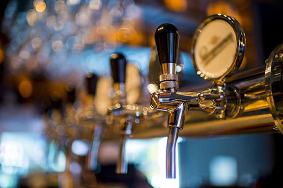 A close up of a beer tap with a gauge on it.