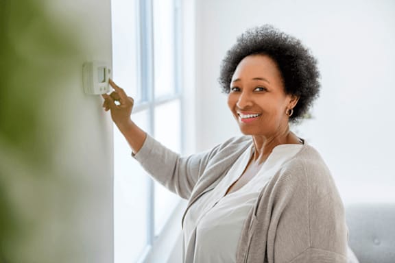 A woman is adjusting a light switch.