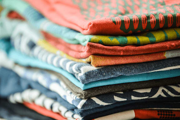 A stack of folded clothes with various patterns and colors.