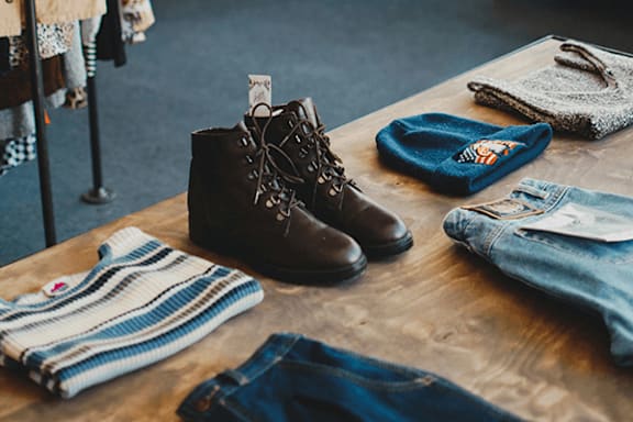 A pair of brown boots is on display with other clothing items.
