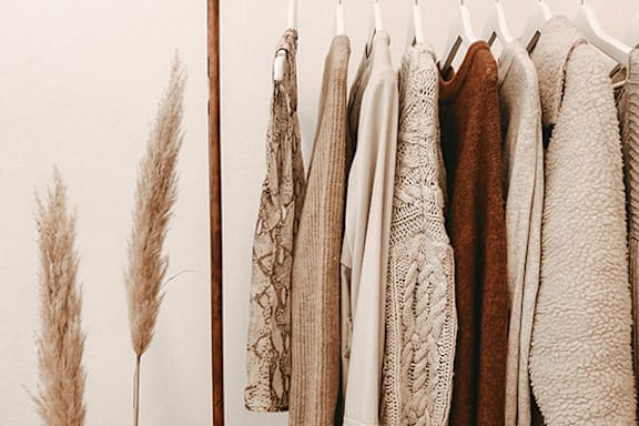 A row of hanging sweaters in various colors.