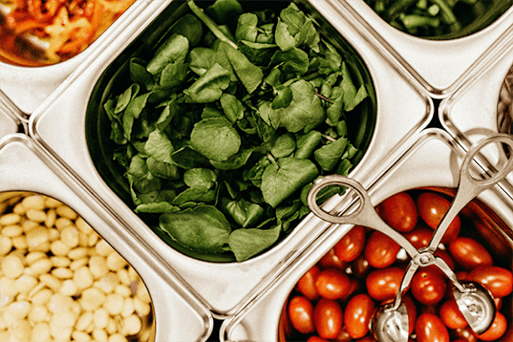 A close up of a metal tray with four compartments, each holding a different food item.