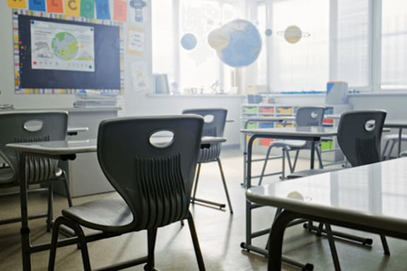 A classroom with chairs and tables arranged in rows.