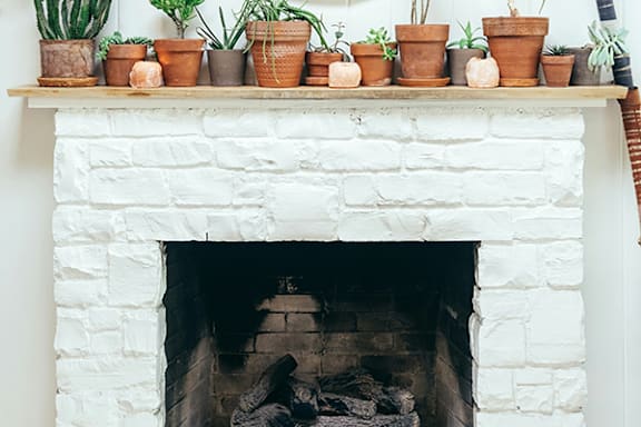 a white fireplace with potted plants on top of it