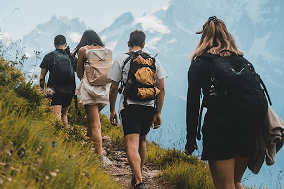 A group of hikers with backpacks walking on a trail.