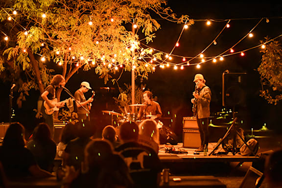 A band performing on stage with string lights above.