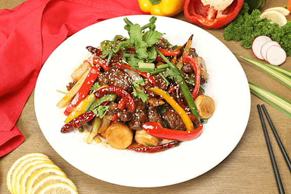 A plate of stir-fried beef with vegetables and garnished with cilantro.