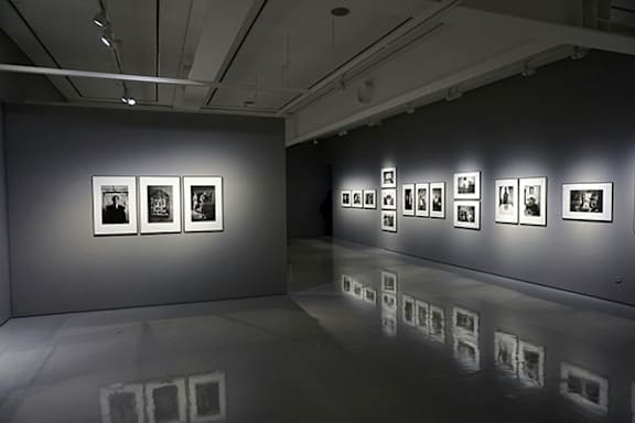 A gallery with a white wall and pictures on it.