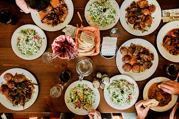 A group of people are gathered around a wooden table, enjoying a meal together.
