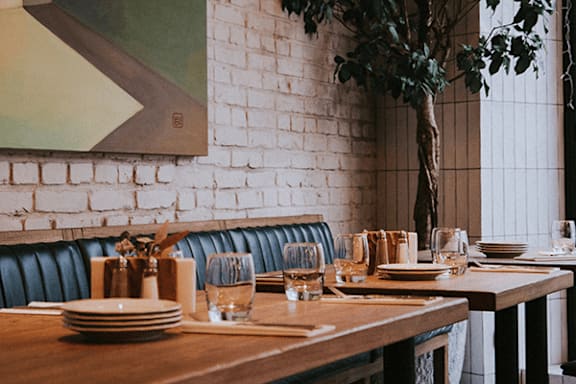 A dining table set for a meal with a tree in a vase.
