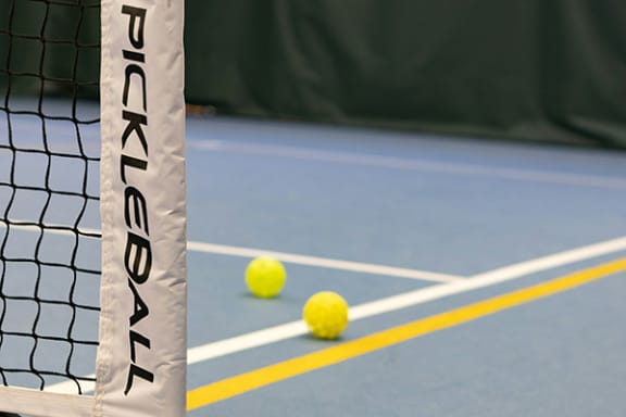two tennis balls on a court with a tennis net