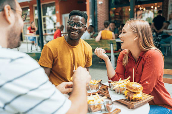 A group of people enjoying a meal together at an outdoor restaurant.