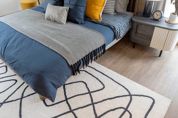 A bed with a blue and grey comforter and a striped pillow.