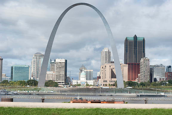 A large arch structure dominates the skyline of a city.