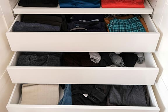 a drawer filled with clothes in a closet