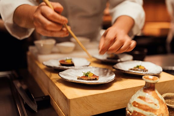 A chef is plating a dish in a restaurant kitchen.