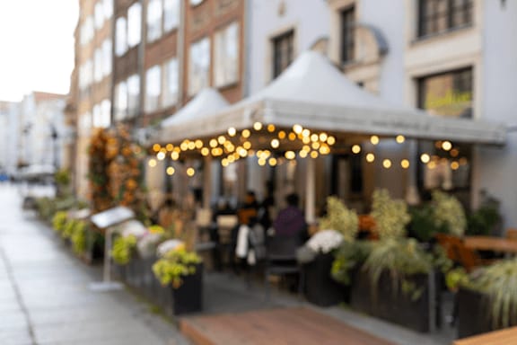 A white tent with lights is set up on a sidewalk.