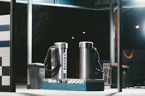 A vacuum cleaner is placed on a platform with a hose connected to a container.