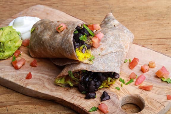 a breakfast burrito on a cutting board