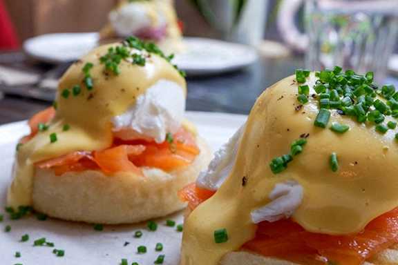 Eggs Benedict with smoked salmon and hollandaise sauce on a white plate.