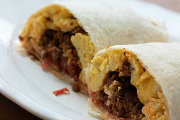 A close up of a burrito cut in half, showing the filling.