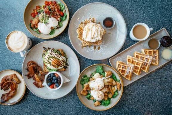 a table topped with plates of breakfast food and waffles