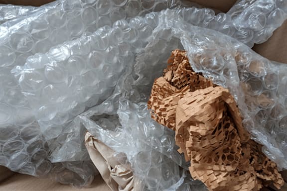 A crumpled brown paper bag is partially covered by a plastic bag.