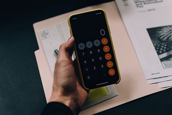 a hand holding a smartphone over a desk
