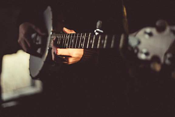 A person playing a guitar in a dimly lit room.
